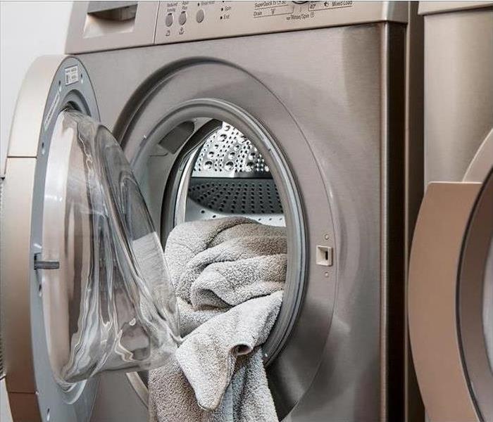 An open washing machine with a towel sticking out