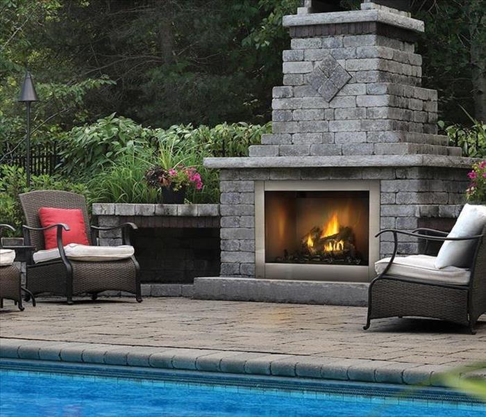 Outside space with chairs and lit fireplace.